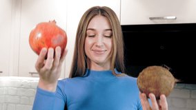 healthy lifestyle. healthy food. young, smiling, beautiful woman holds a pomegranate and coconut in her hands and doubts, trying to make a choice. nutritionist.