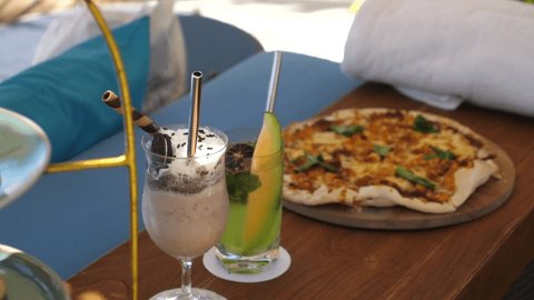 Lunch at the poolside: pizza, chocolate milkshake and pralines on a cake stand 