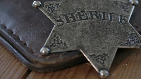 A sheriff badge from the wild west rack focus to leather identification wallet on wood background