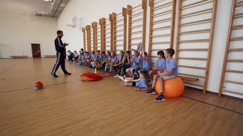 Kyiv, Ukraine - October 2020. A physical education teacher conducts a lesson in the gym with children. Children actively behave and listen carefully to the teacher