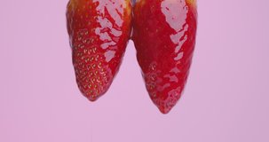 Strawberry jam drops flows down from natural bio red appetizing berries on pink studio background with copy space