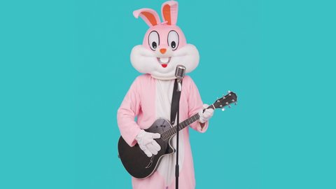 Guitarist plays acoustic guitar, sings song to retro vintage classic microphone, celebrates Happy easter