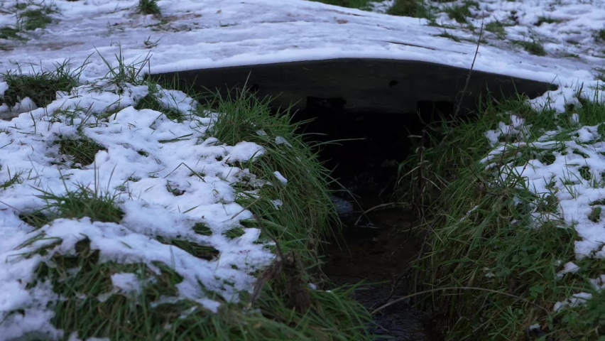 Small wooden bridge over natural stream covered in snow medium panning shot