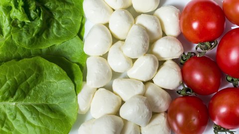 4k footage. ingredients of caprese salad in the form of the flag of italy. mozzarella cheese, basil and tomatoes lie on the table symbolizing the flag of italy. camera movement. the camera moves away 