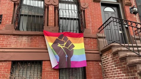 Harlem, NY, USA - February 10, 2021: A BLM Pride flag hangs outside of a Harlem row house