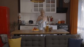 Young headscarved woman, singing and dancing with a whisk in the kitchen. Young headscarved  woman having fun alone while cooking. Slow motion video.