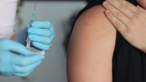 Close up shot of a nurse injecting vaccine into patient's arm then cleaning it with sterile gauze