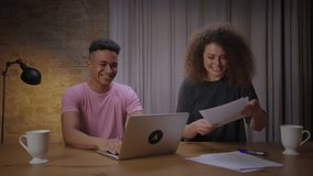 Young mixed race couple passed online exam together. Happy millennial African American student giving high five to female friend for successful exam by internet.