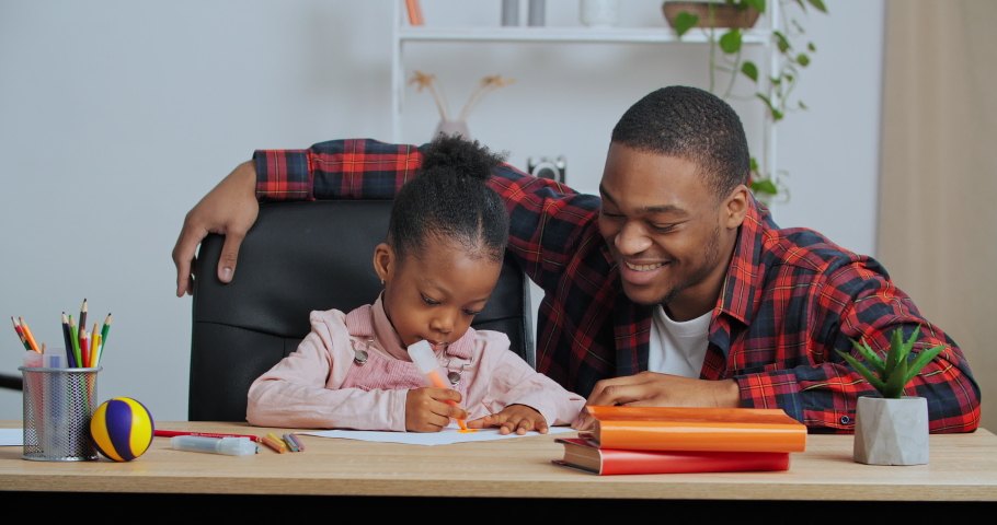 Afro american guy loving father helping little cute preschool daughter to draw picture do homework supports child gives five hands gesture of approval for teamwork excellent results, home teaching Royalty-Free Stock Footage #1067262463