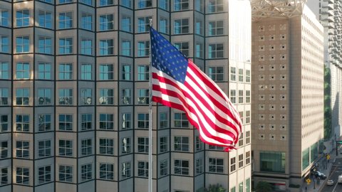 Patriotic aerial of vibrant flag of United States of America flattering with modern building on background in financial district in downtown Miami, Florida USA. President and Independence day drone 4K