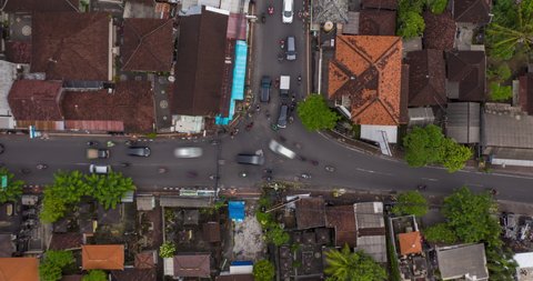 Top down overhead aerial view timelapse of busy rush hour traffic at the intersection in Canggu, Bali. Typical busy car and motorcycle traffic at urban crossroads on the streets of Bali, Time Lapse