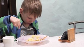 the child eats and looks at the phone