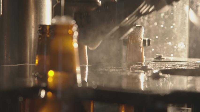 Close-up of bottles getting filled with beer on a modern industrial machine. Foam getting out of bottles and overflowing. Factory, brewery concept. Royalty-Free Stock Footage #1067276002