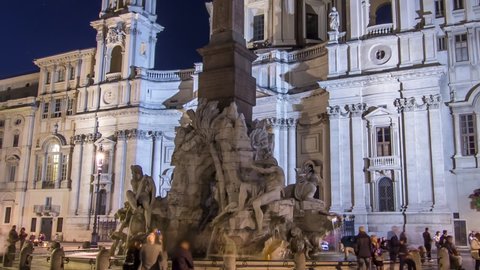 Illuminated at night the fontana of the Four Rivers timelapse hyperlapse on Piazza Navona on the Sant'Agnese in Agone church background, Rome, Italy. Tourists and illuminated old buildings