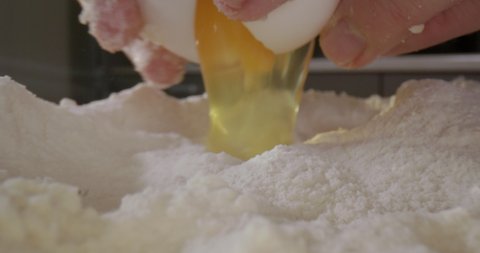 The egg is made into flour and the yolk with the protein falls into the flour. The process of making dough for cakes or pizza in the kitchen. Time-lapse 4K macro video beautiful background.
