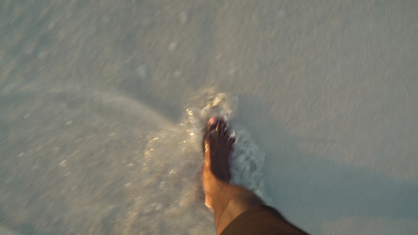 Close up view of an adult black male walking on a beautiful beach during sunset. African American male feet walking on the beach.   Royalty-Free Stock Footage #1067280889