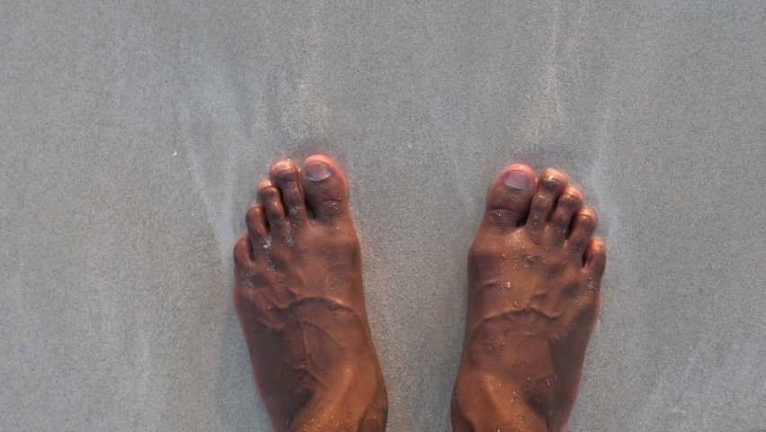 Close up view of an adult black male looking at his feet while standing on the beach. African American black male feet. Close up view of veins and arteries on a human feet.  | Shutterstock HD Video #1067280901