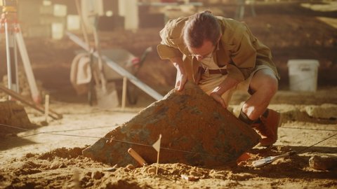 Archaeological Digging Site: Great Male Archeologist Work on Excavation Site, Carefully Cleaning, Lifting Newly Discovered Ancient Civilization Cultural Artifact, Historic Clay Tablet. Slow Motion
