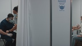 Doctors administering vaccine to a patients inside temporary vaccination cabins. COVID-19 coronavirus vaccination - Powered by Shutterstock - Get 15% off with code: PIKWIZARD15