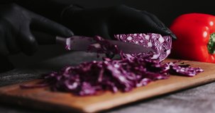 4K Women Hand cutting fresh red cabbage on Cutting Board. Female hand slices raw red cabbage into little slide with knife on cutting Board. healthy food concept