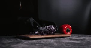 4K Women Hand cutting fresh red cabbage on Cutting Board. Female hand slices raw red cabbage into little slide with knife on cutting Board. healthy food concept