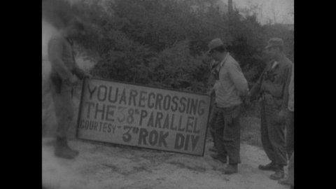 1950s: Soldiers hold sign for 38th Parallel. Soldiers walk down road. People hold white flags. Cemetery of crosses. Soldier lays wreath on grave then salutes.