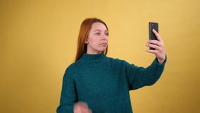 Amazing cheerful young woman in green sweaters taking selfie. isolated on yellow background
