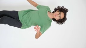 vertical video. handsome stylish guy with curly hair dancing on a white background.
