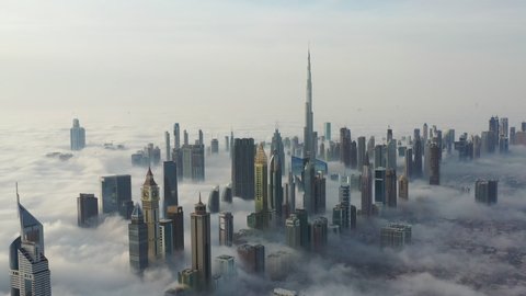 Aerial birds eye view of Dubai city urban futuristic skyline during fog; panning shot of Dubai 