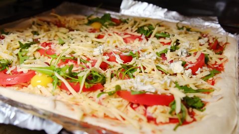 A woman prepares homemade pizza. sprinkles it with cheese.