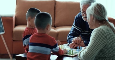 Grandparents play board games with twin grandchildren. Family fun and free time, board games