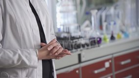Female Hands of a scientist in a white coat on the background of a table with scientific equipment. Glass flasks with yellow, blue, red liquids in the laboratory in high resolution. Video in the hlg c
