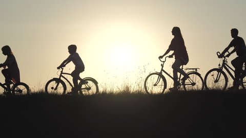 Silhouettes of a large large family on bicycles at sunset.