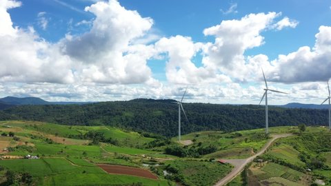 Aerial view of Powerful wind turbine farm for alternative energy production on clouds blue sky warm summer at highland. Cenerating clean renewable energy for sustainable development