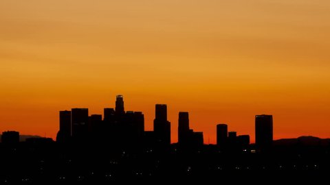 4K Time lapse zoom out sunrise over downtown Los Angeles skyline silhouette with red and orange colored sky