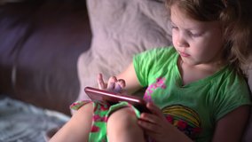 Girl watching cartoon using tablet. little daughter plays games on smartphone. 