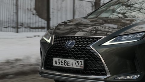 Moscow, Russia - CIRCA 2020: large green Lexus RX SUV drives on winter road in city. View on large front grille with logo.