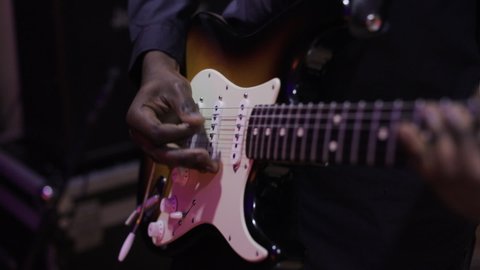 Musician playing the guitar during a live performance. Strumming electric guitar. A musician plays music. Human hands playing on electric guitar. Fingers on guitar strings