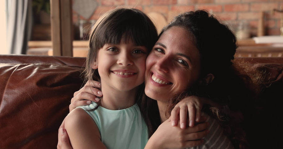 Close up view young lovely mom and little adorable 10s daughter cuddling with eyes closed enjoy sweet moment seated on couch at home. Love and caress, adoption and custody, happy Mother day concept Royalty-Free Stock Footage #1067349511