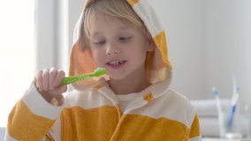 Slow motion video of boy cleaned teeth with dental floss and then is brushing his teeth with toothbrush carefully. Learning children proper oral hygiene. Dental medicine and healthcare for kids.