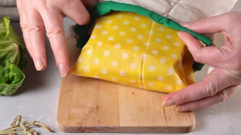 Zero waste and plastic free concept. Woman hands wrapping a healthy vegan sandwich in beeswax food wrap for lunch. Eco-friendly, reusable wax cloth and cotton bags. 4K UHD