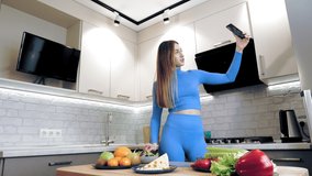 cooking online. healthy food. Woman blogger taking selfie, shooting video about vegetarian lunch on smartphone for social media, at home kitchen. culinary vlogging, social networks.