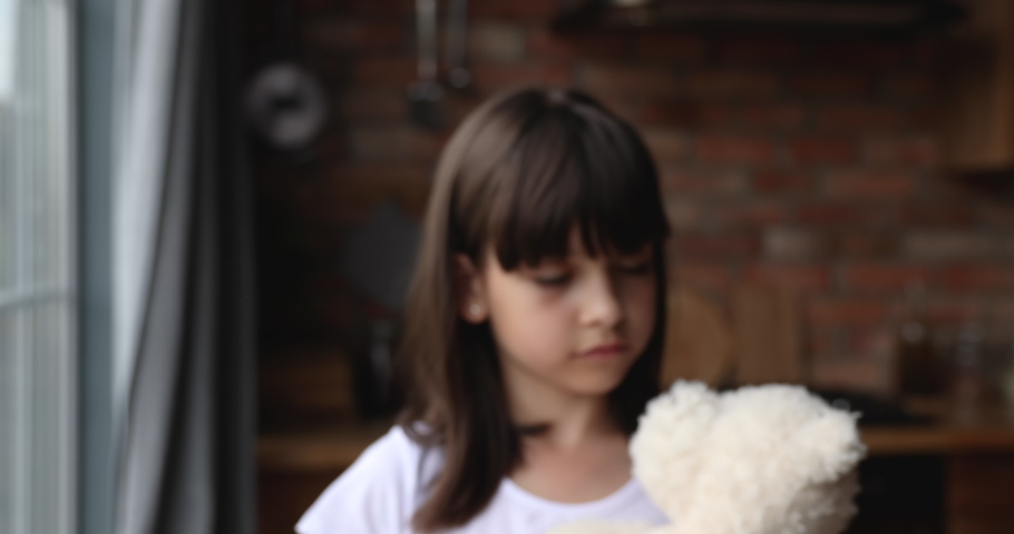 Little lonely girl standing indoor holds stuffed toy outstretching palm to camera makes protective gesture. Social issues, stop child abuse, bullying, discrimination, violence against children concept Royalty-Free Stock Footage #1067355226