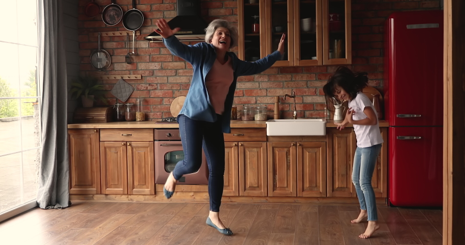 Active 60s grandma joyful 10s grandkid having fun in kitchen dancing listen rock music pretend be superstar, kid shake head imagine play guitar enjoy carefree weekend with granny. Home hobby concept Royalty-Free Stock Footage #1067355289