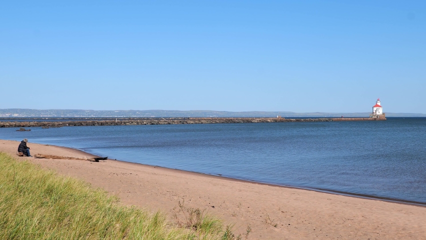The lake shore and ship channel at Wisconsin Point in Superior, with the blue water of Great Lake Superior and Duluth, Minnesota in the distance, on a sunny day.