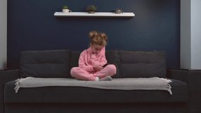 small girl on a couch is addicted to the phone spending time using it