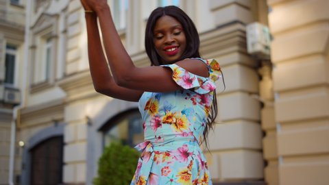 African american girl making body moves in city. Positive african female professional practicing latino dance outdoors. Energetic afro woman dancing bachata on street in slow motion.