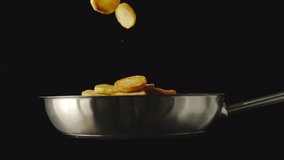 SLOW MOTION: Roasted potatoes fall into a steel frying pan on black background - Powered by Shutterstock - Get 15% off with code: PIKWIZARD15