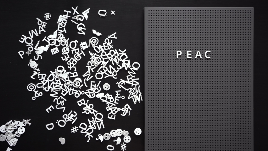 Thin female hand lays out words PEACE on a dark grey board Calm and peaceful life concept. Harmony with yourself Copy space 