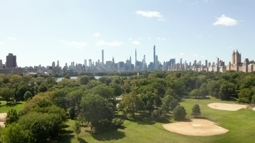 Manhattan Skyscrapers revealing behind beautiful Green Nature with Trees and Lake in Central Park, New York City, Aerial Wide View Royalty-Free Stock Footage #1067373674